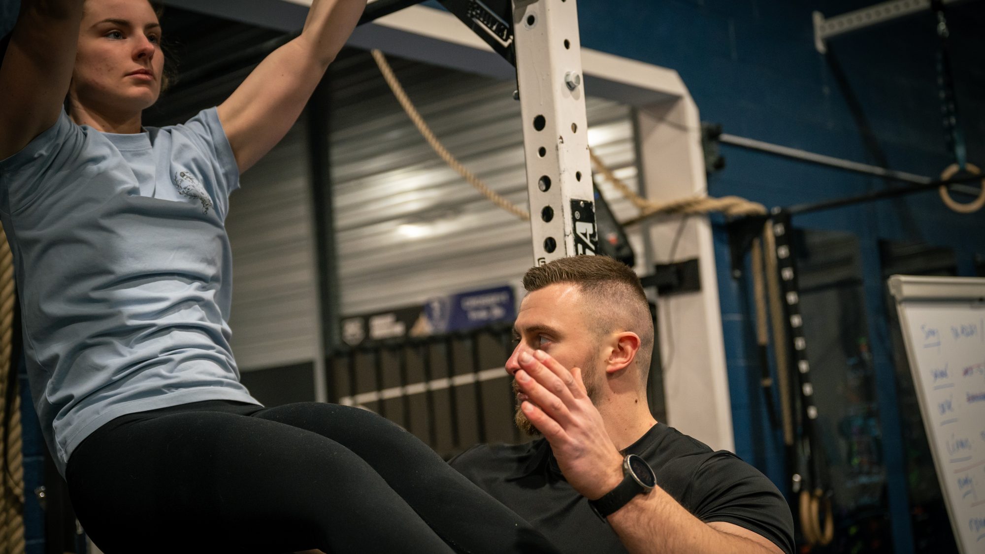Rudy Tarlet en posture d'analyse coachant une athlète aux toes-to-bar en box CrossFit